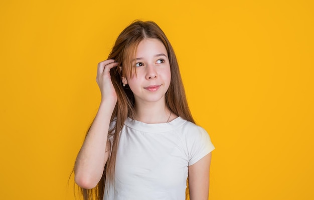 Haar Schönheit und Gesundheit niedliche Schönheit hat lange brünette Haare Mode-Stil fröhliches Mädchen auf gelbem Hintergrund Teenager-Kind in lässigem weißem Hemd Kindheitsglück