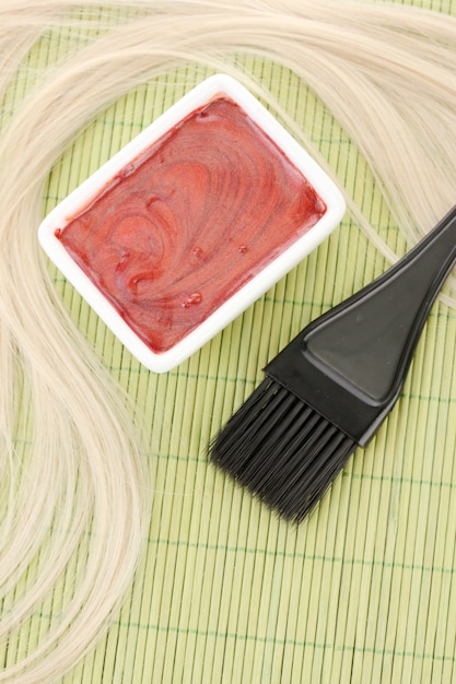 Haarfärbemittel in Schüssel und Pinsel zum Färben der Haare auf grüner Bambusmatte