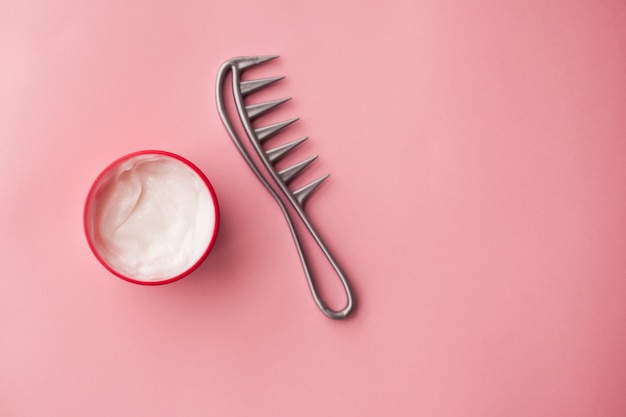 Haarmaske und Haarbürste auf einem rosa Hintergrund. Haarpflege. Haarlaminierung. Milch in Kosmetikgläsern,