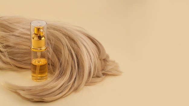 Haaröl und blondes Haar auf beigem Hintergrund in Form eines Banners