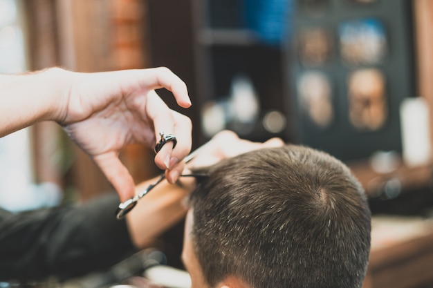 Haarschnitt beim Friseur. Barber schneidet dem Kunden die Haare auf den Kopf. Der Prozess der Erstellung von Frisuren für Männer. Ein Mann in einem Friseurladen. Der nahe Plan. Gerätestylist. Selektiver Fokus