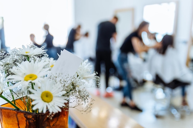 Foto haarschnitt salon auf hintergrund kamille in vase aus nächster nähe