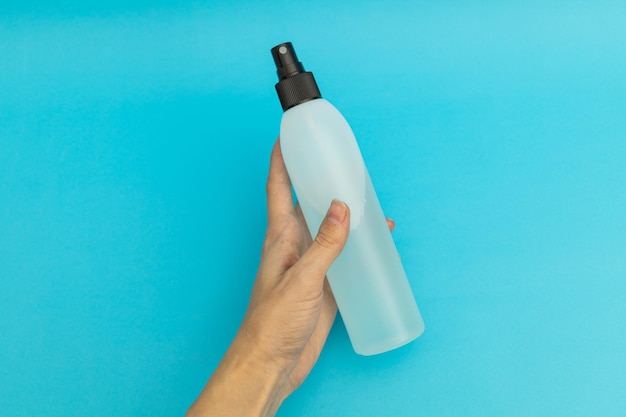 Haarspray in blauer Plastikflasche auf blauem Hintergrund monochrom