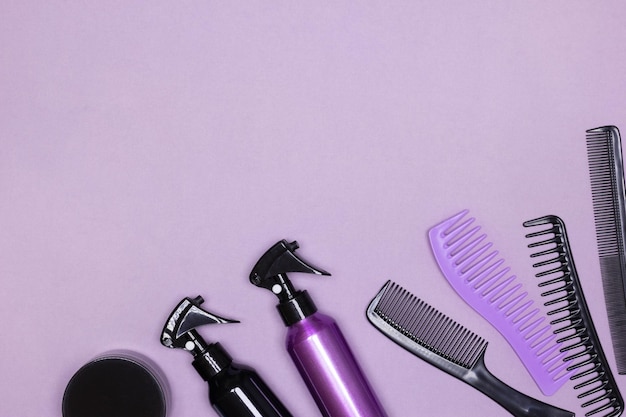 Haarstyling-Produktflaschen mit Kämmen auf violettem Hintergrund. Flach liegen. Platz kopieren