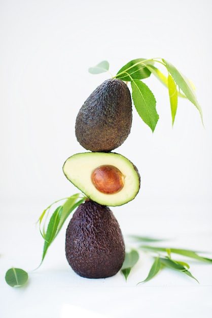 Haas Avocado mit Blättern auf weißem Hintergrund, selektiver Fokus, kreatives Bild