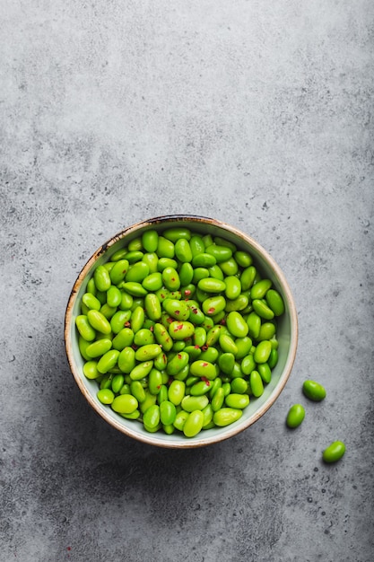 Habas de edamame verdes maduras frescas sin vainas en un tazón sobre fondo de piedra gris. Vista superior, de cerca. Merienda asiática ligera y saludable, buena fuente de proteína vegetariana para la dieta y la nutrición.