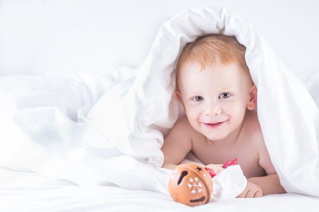 Habby junger lächelnder Kinderjunge im weißen Bett.