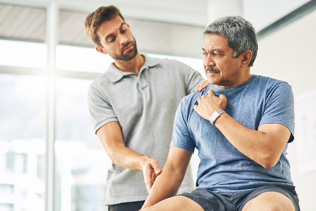 Haben Sie gerade Schmerzen Schnappschuss eines jungen männlichen Physiotherapeuten, der einem älteren Patienten bei der Genesung hilft