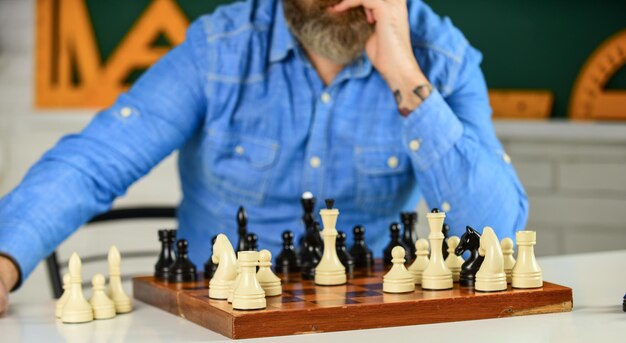 Habilidades de torneo. Figuras de ajedrez sobre tablero de madera. Maestra de escuela enfocada. pensando en atacar y capturar piezas de ajedrez del oponente. pensando en el próximo movimiento. hombre entrenando para competición de ajedrez.