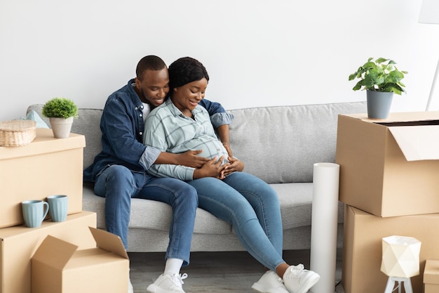 Habitação familiar. feliz casal afro-americano expectante sentado no sofá em novo apartamento