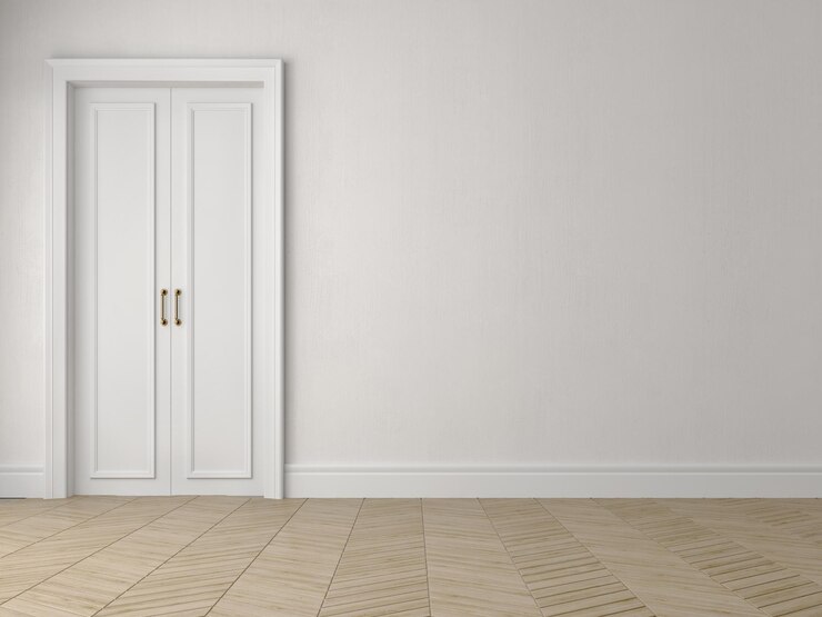 Habitación blanca vacía con puerta y suelo de parquet de madera.