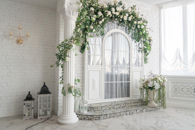 Una habitación blanca con ventana y flores en la pared.