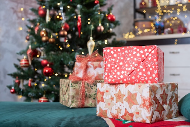 Habitación decorada con abeto con adornos de bolas rojas y doradas, guirnaldas de luz, cajas de regalo para Navidad y año nuevo.