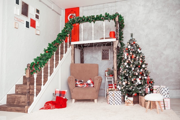 Habitación de dos pisos en un estilo clásico de Año Nuevo con una silla grande y un árbol de Navidad