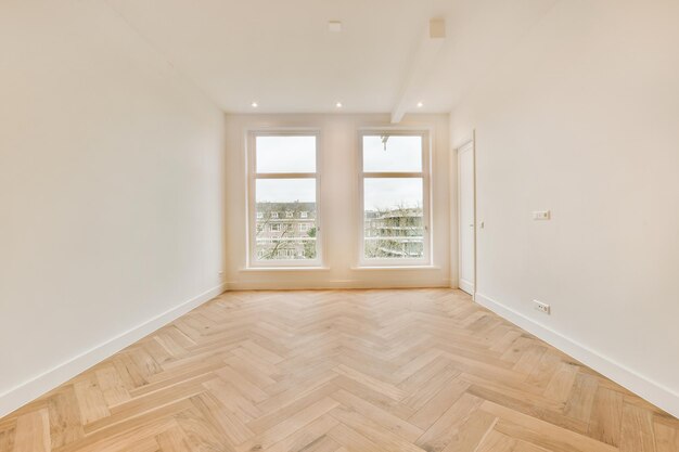 Una habitación espaciosa con suelos de parquet en colores vivos y grandes ventanales en una casa moderna