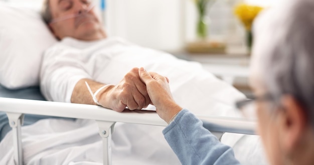 La habitación del hospital y la pareja de ancianos tomados de la mano la empatía y el apoyo al marido la recuperación del problema de atención médica o la rehabilitación la comodidad de la jubilación o el cuidado de una mujer anciana para un paciente con cáncer enfermo en la cama