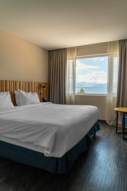 habitación de hotel cama doble con sábanas blancas y vistas a la montaña
