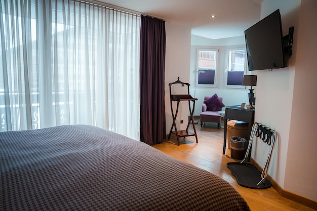 Habitación de hotel de lujo con cama grande, portaequipajes de madera y TV de pantalla plana en Zermatt, Suiza