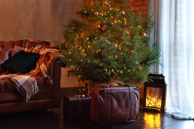 Habitación interior tipo loft con sofá y abeto de Navidad con guirnaldas de luces brillantes