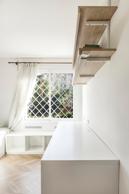 Habitación juvenil con escritorio y librería junto a una ventana con celosía blanca