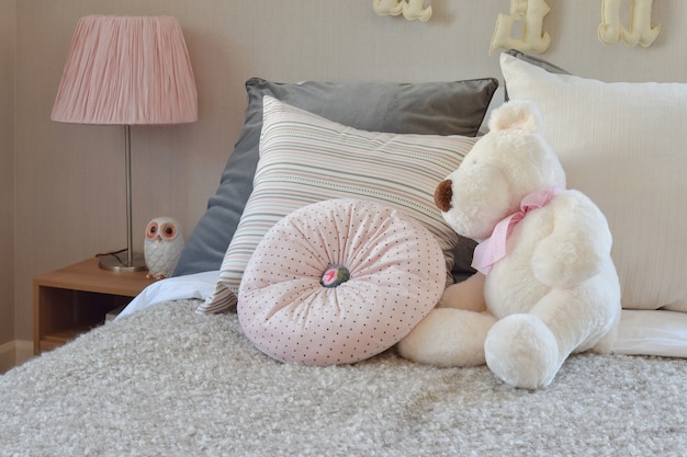 Habitación moderna para niños con muñeca y almohadas en la cama.