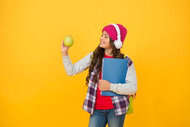 Hábitos alimentares saudáveis para o seu filho garota feliz segura fundo amarelo maçã desfrutando de lanche escolar saudável lanches e dieta saudáveis oferecendo comida saudável na escola educação on-line