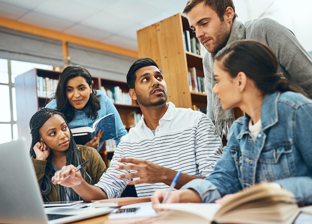 Hablando de educación y estudiantes estudiando en una biblioteca para un trabajo en equipo de proyecto grupal y aprendiendo Computadora portátil de diversidad y amigos hablando sobre notas universitarias conocimiento y planificación de investigación