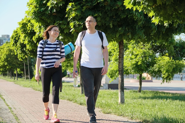 Hablando de hombre y mujer de mediana edad, pareja caminando por la carretera del parque