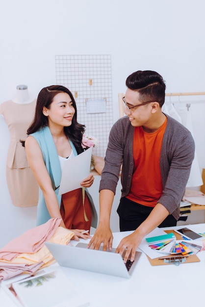 Hablando de nuevo diseño de moda. Hermosa joven hablando con su pareja mientras trabajaban juntos en el taller