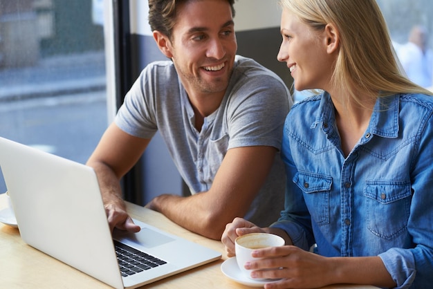 Hablando portátil o pareja feliz en una cafetería o cafetería en el sitio web para reservar unas vacaciones de vacaciones Amor hombre o mujer en la tecnología para la investigación de compras en línea o redes sociales con taza de té o sonrisa