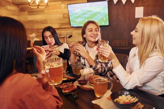 Foto hablando entre sí grupo de jóvenes amigos sentados juntos en un bar con cerveza