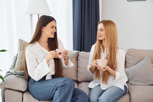 Hablando entre sí La madre joven con su hija está en casa durante el día