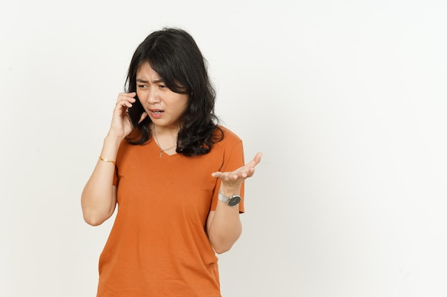 Hablando por teléfono con expresión seria enfadada de mujer asiática con camiseta naranja