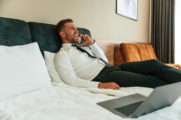 Hablando por teléfono El hombre de negocios está adentro en la habitación del hotel