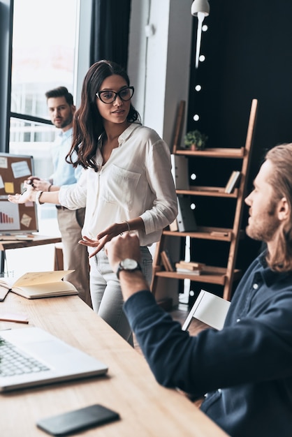 Hablar de ideas arriesgadas. Tres jóvenes empresarios discutiendo algo mientras trabajaba en la oficina