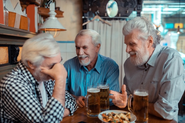 Hablar de partido de fútbol. Pensionistas canosos alegres discutiendo el partido de fútbol en el pub