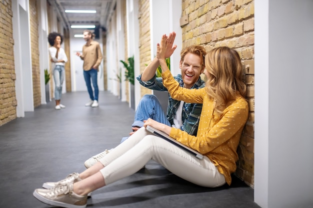 Hablar del trabajo. Dos colegas sentados en el suelo en el pasillo y discutiendo algo