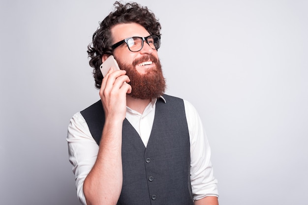 Hablemos contigo, hombre barbudo guapo y encantador en traje hablando por teléfono con alguien