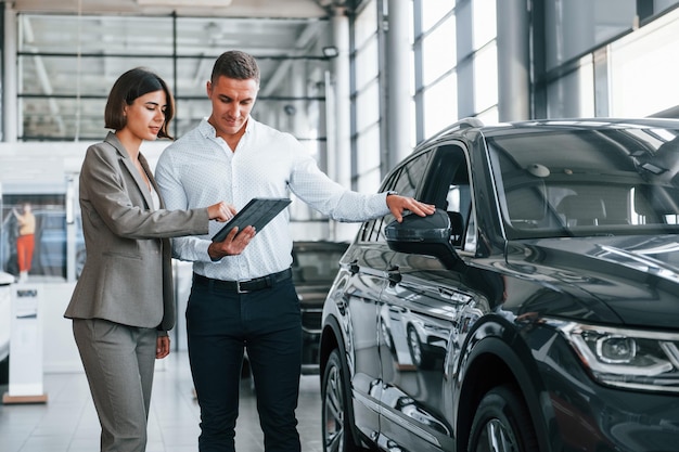 Foto hacer un acuerdo hombre en ropa formal ayudando al cliente con la elección del automóvil