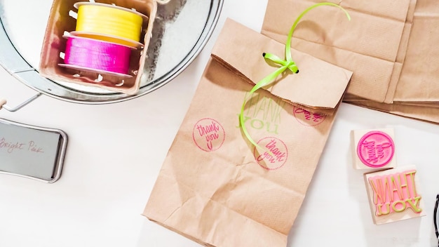 Hacer bolsas de regalos con bolsas marrones con sellos y cintas para la fiesta de cumpleaños de los niños.