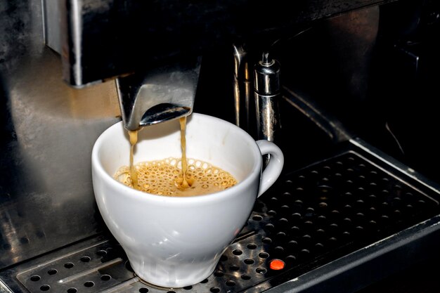 Hacer café en una máquina de café con taza blanca