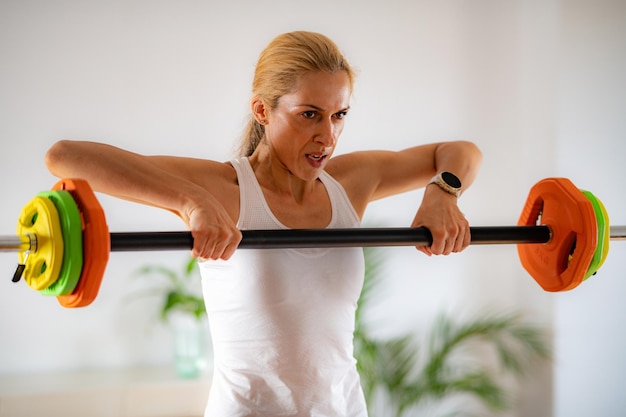 Hacer ejercicio en casa mujer usando barra de pesas con pesas para entrenamiento de fuerza