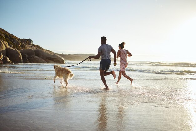 Hacer ejercicio con la pareja y el perro en la playa para correr, entrenar y hacer ejercicio, cardio y espacio para maquetas Bienestar familiar y entrenamiento de mascotas al amanecer en el océano y correr en el agua mientras se unen con su labrador