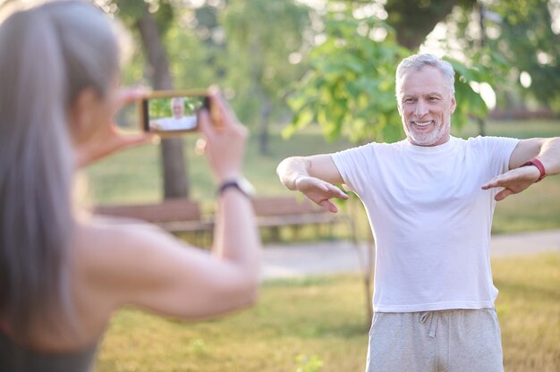 Hacer fotografías. Una mujer haciendo una foto de su marido mientras hace ejercicio.