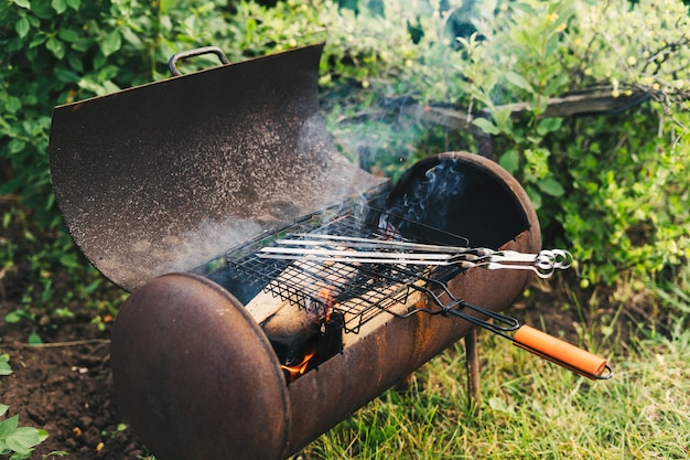 Hacer un fuego en la parrilla para la llama de la barbacoa en el fondo de la hierba verde por la noche en el