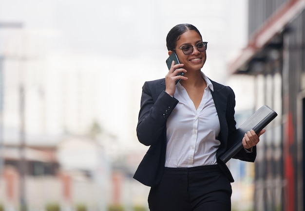 Hacer esas llamadas importantes a primera hora de la mañana. Foto de una atractiva joven empresaria caminando por la ciudad y usando su teléfono celular durante su viaje matutino.