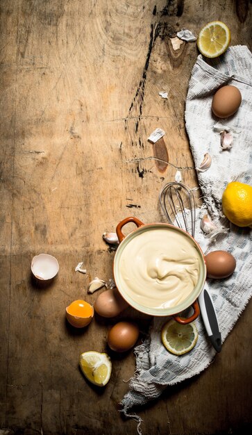 Hacer mayonesa con huevos, ajo y limón sobre fondo de madera