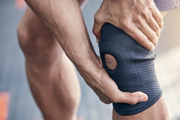 Hacer muchos ejercicios de alto estrés puede lastimar su rodilla. Captura de pantalla de un hombre irreconocible sosteniendo su rodilla con dolor mientras hace ejercicio en un gimnasio.