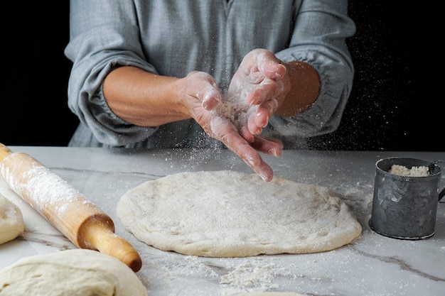 Hacer pizza, mano de mujer trabajando con masa y harina