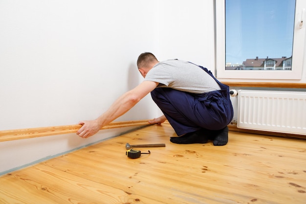 Para hacer reparaciones Instalación de un nuevo zócalo un hombre hace reparaciones en una habitación